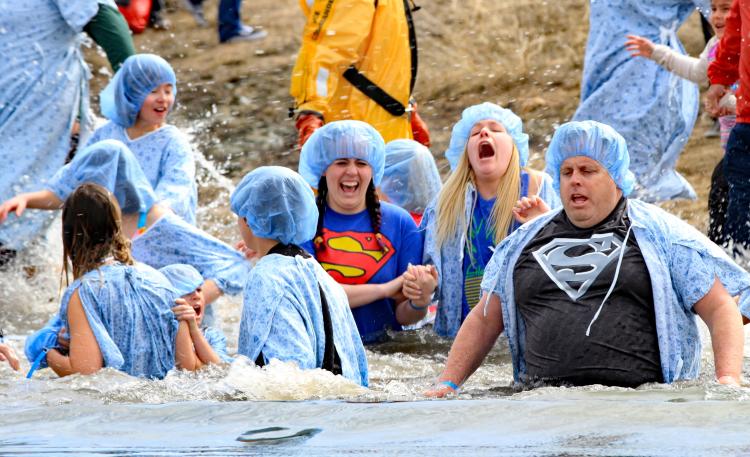 A group of men and women wear hospital gowns and caps as they plunge into Big Bear Lake during the Big Bear Polar Plunge.